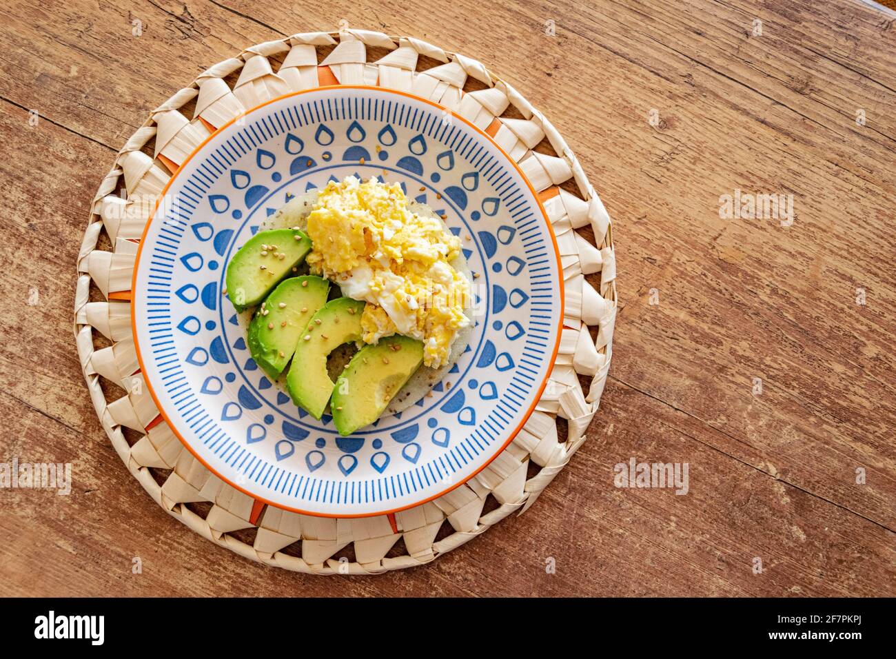 Un piatto di uova strapazzate servito insieme a fette di fresco avocado su un pezzo di pane di farina di mais Foto Stock