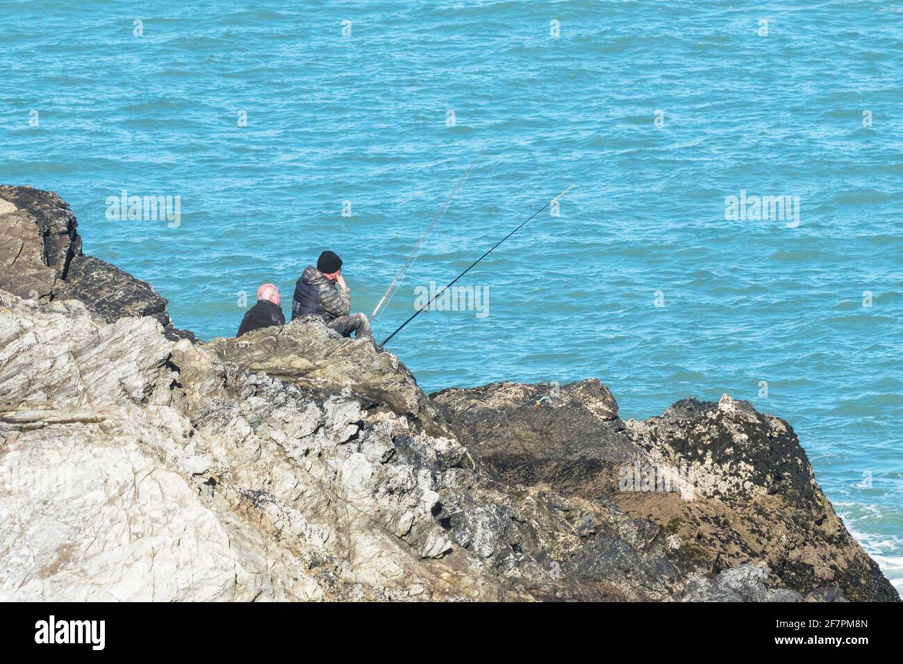 Uomini maturi che pescano dalle rocce a Towan Head a Newquay in Cornovaglia. Foto Stock