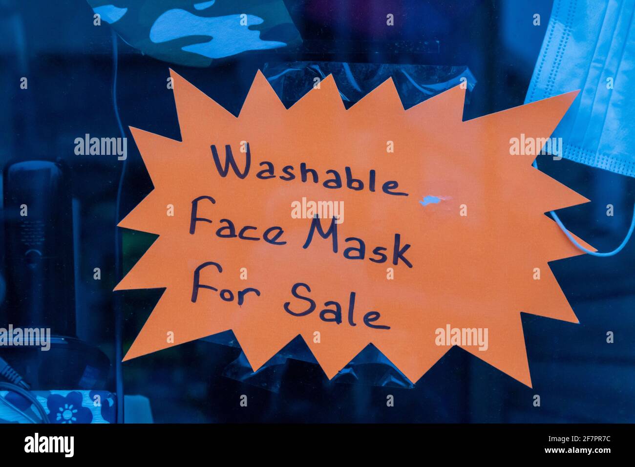Un segno arancione brillante scritto a mano che fa pubblicità a maschere lavabili per il viso in vendita. Foto Stock