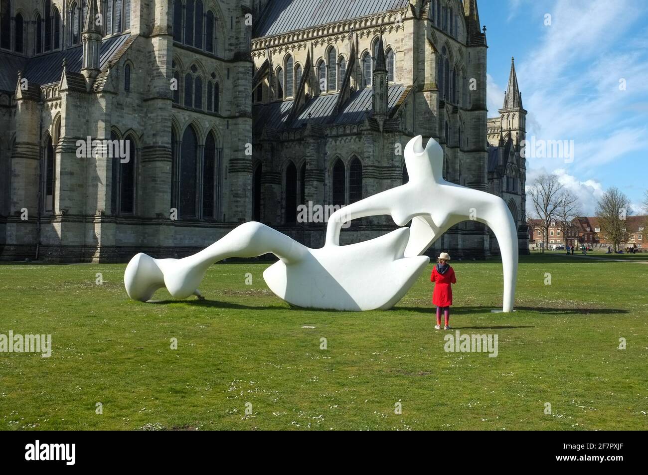 Grande scultura di figura di reclining di Henry Moore che è esaminato da una ragazza giovane in rosso alla cattedrale di Salisbury vicino nel Wiltshire. REGNO UNITO. Aprile 2021. Foto Stock