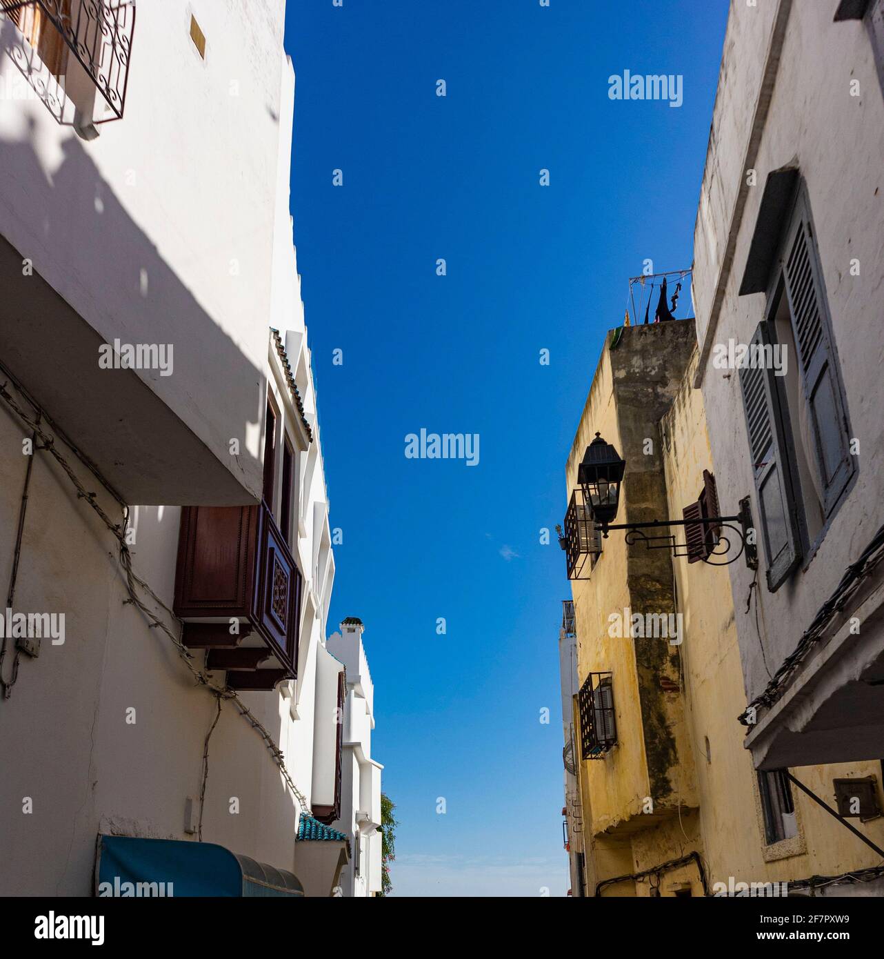 Una vista della strada e del cielo blu in una strada stretta che guarda attraverso gli appartamenti che costeggiano ogni sid delle strade. Foto Stock