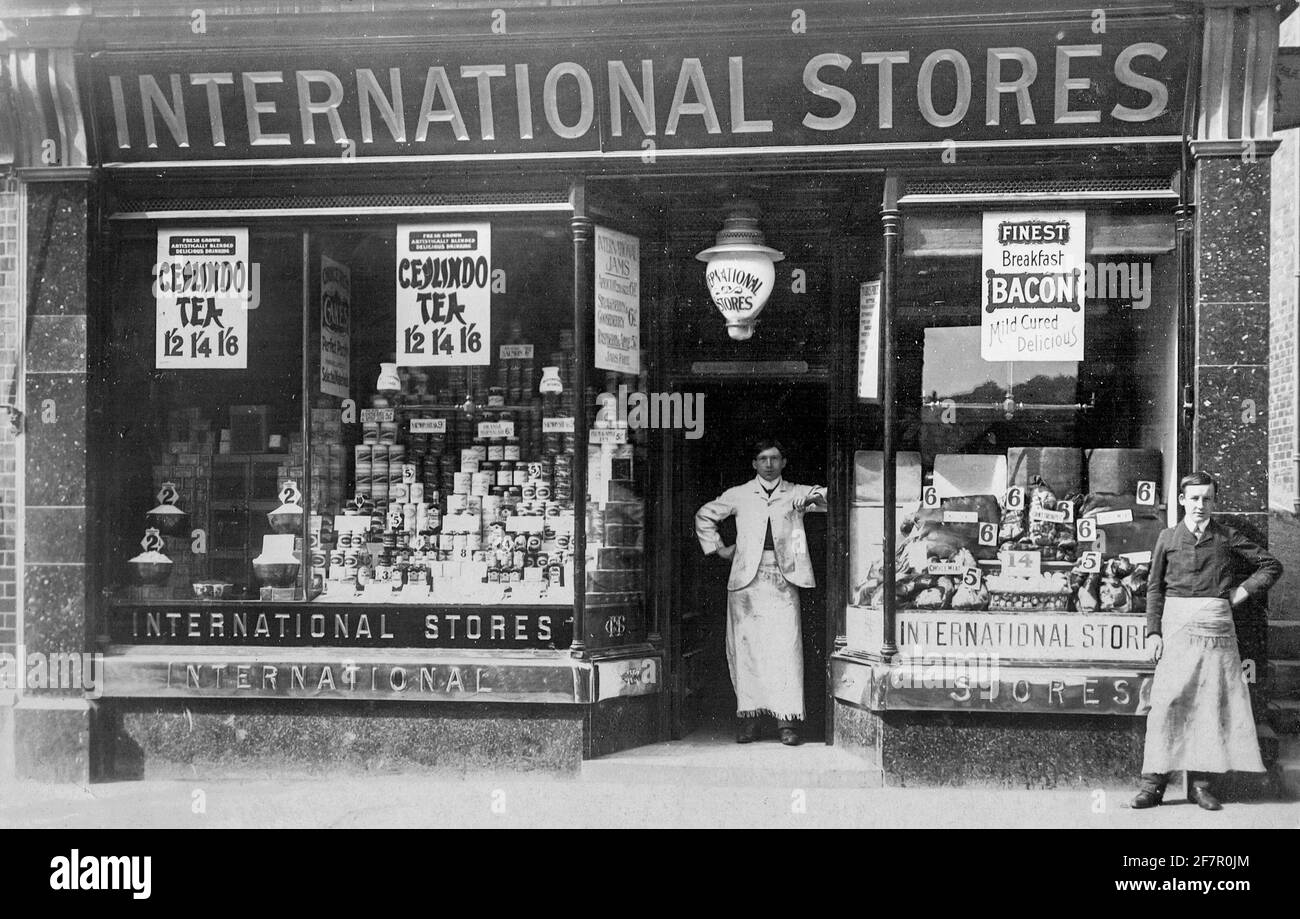 Inizio del ventesimo secolo Fotografia di due negozianti di fronte ad una filiale di negozi internazionali un negozio di alimentari in Matlock Derbyshire Inghilterra UK. Foto Stock