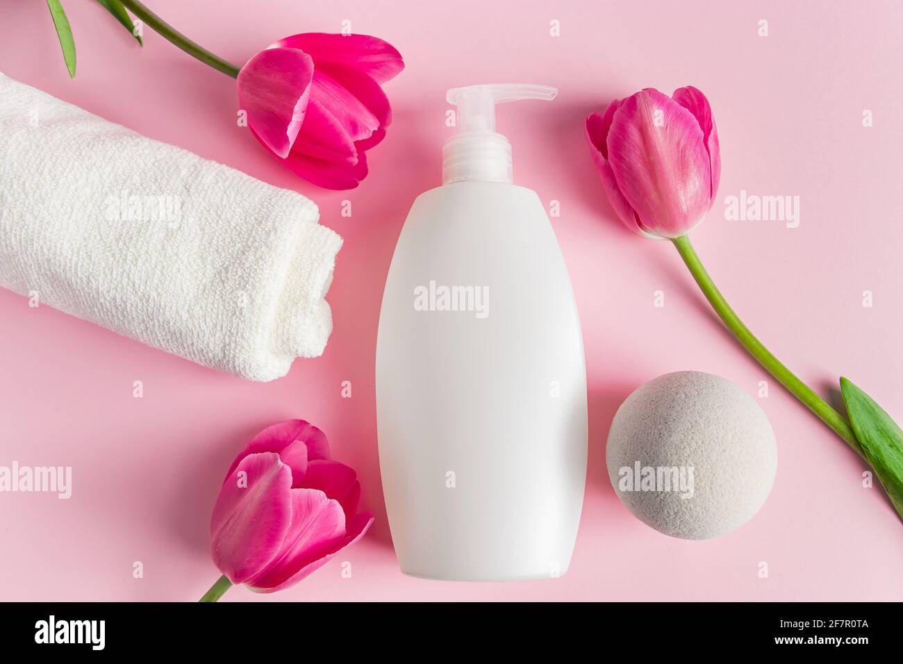 Prodotti per la cura della pelle Spa su sfondo rosa. Cosmetici naturali e tulipani rossi. Posiziona per il testo. Foto Stock