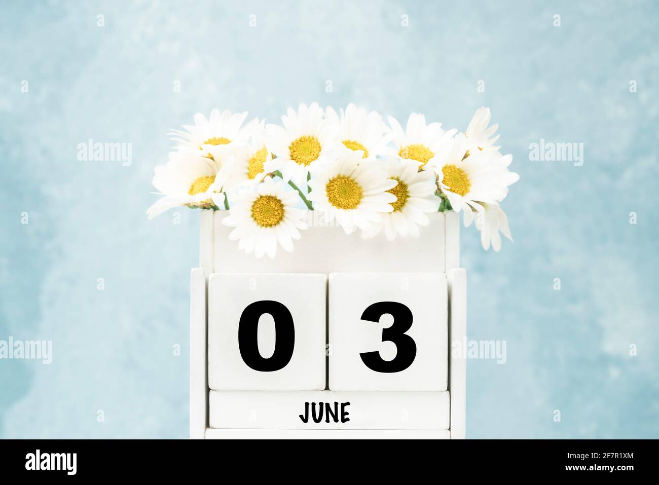 Calendario cubo bianco per giugno con fiori margherita su blu sfondo con spazio di copia Foto Stock