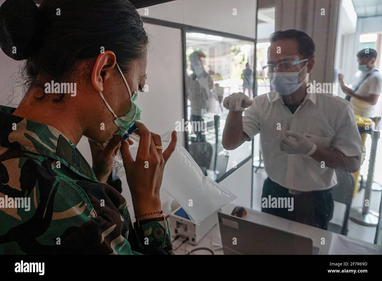 Una donna soffia aria in un sacchetto di plastica per essere testato per la malattia del coronavirus (COVID-19) utilizzando un GeNose C19 (GeNose), uno strumento di rilevamento COVID-19 presso l'aeroporto internazionale Gusti Ngurah Rai. Gusti Ngurah Rai International Airport per adottare GeNose C19 coronavirus test per preparare il turismo riapertura. GeNose C19 è un'intelligenza artificiale basata su un metodo di test respiratorio sviluppato dall'Università indonesiana di Gajah Mada, Yogyakarta. (Foto di Dicky Bisinglasi / SOPA Images/Sipa USA) Foto Stock