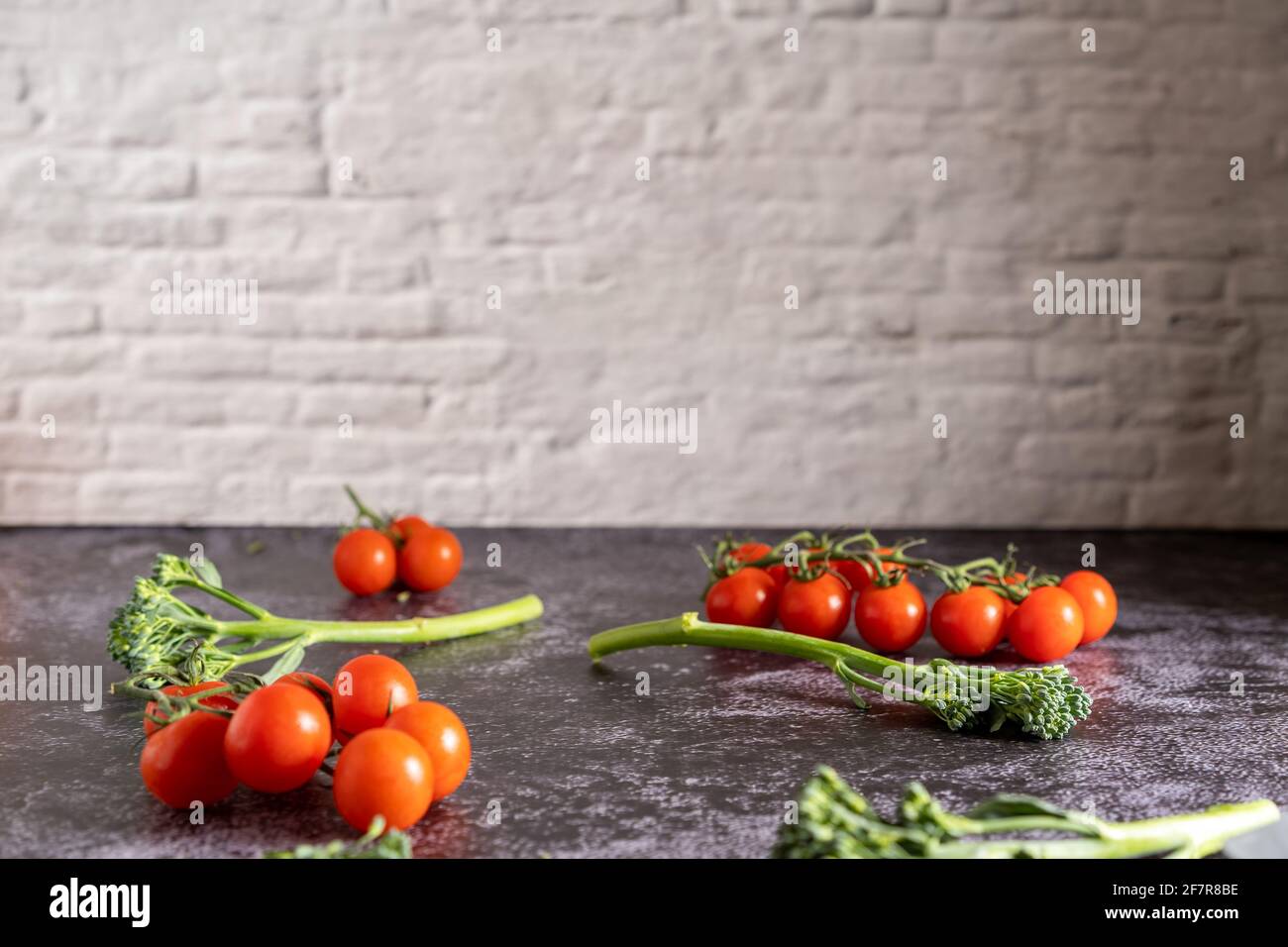Fotografia alimentare di pomodori ciliegini freschi e bimi su un tavolo di pietra con muro di mattoni. Immagini fisse con uno spazio per la copia. Foto Stock