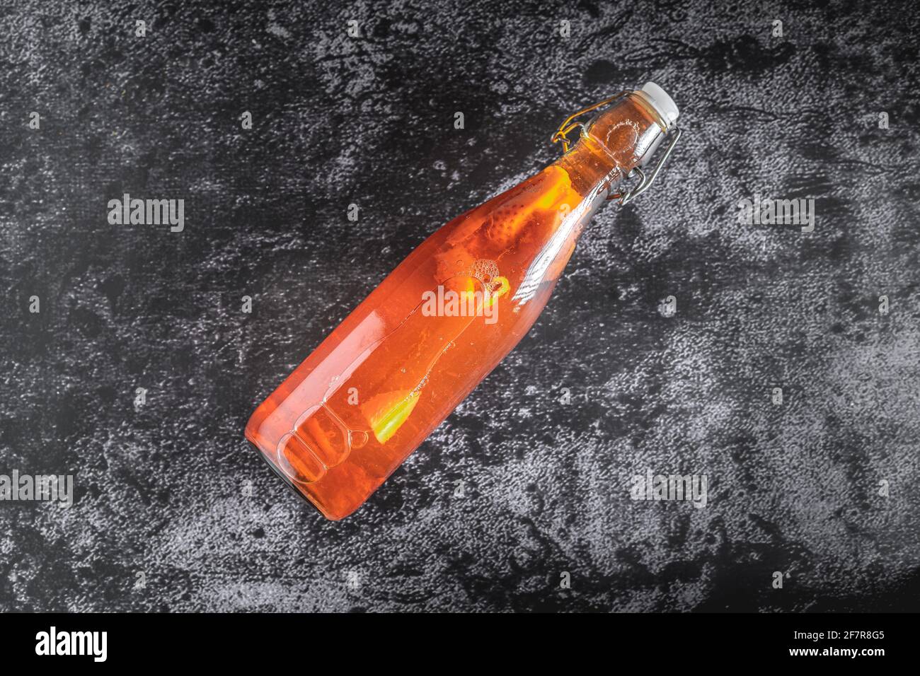 Vista dall'alto di una bottiglia isolata di kombucha fatta in casa, un tè alla frutta con probiotici, batteri e lievito su una pietra nera. Seconda fermentazione con str Foto Stock