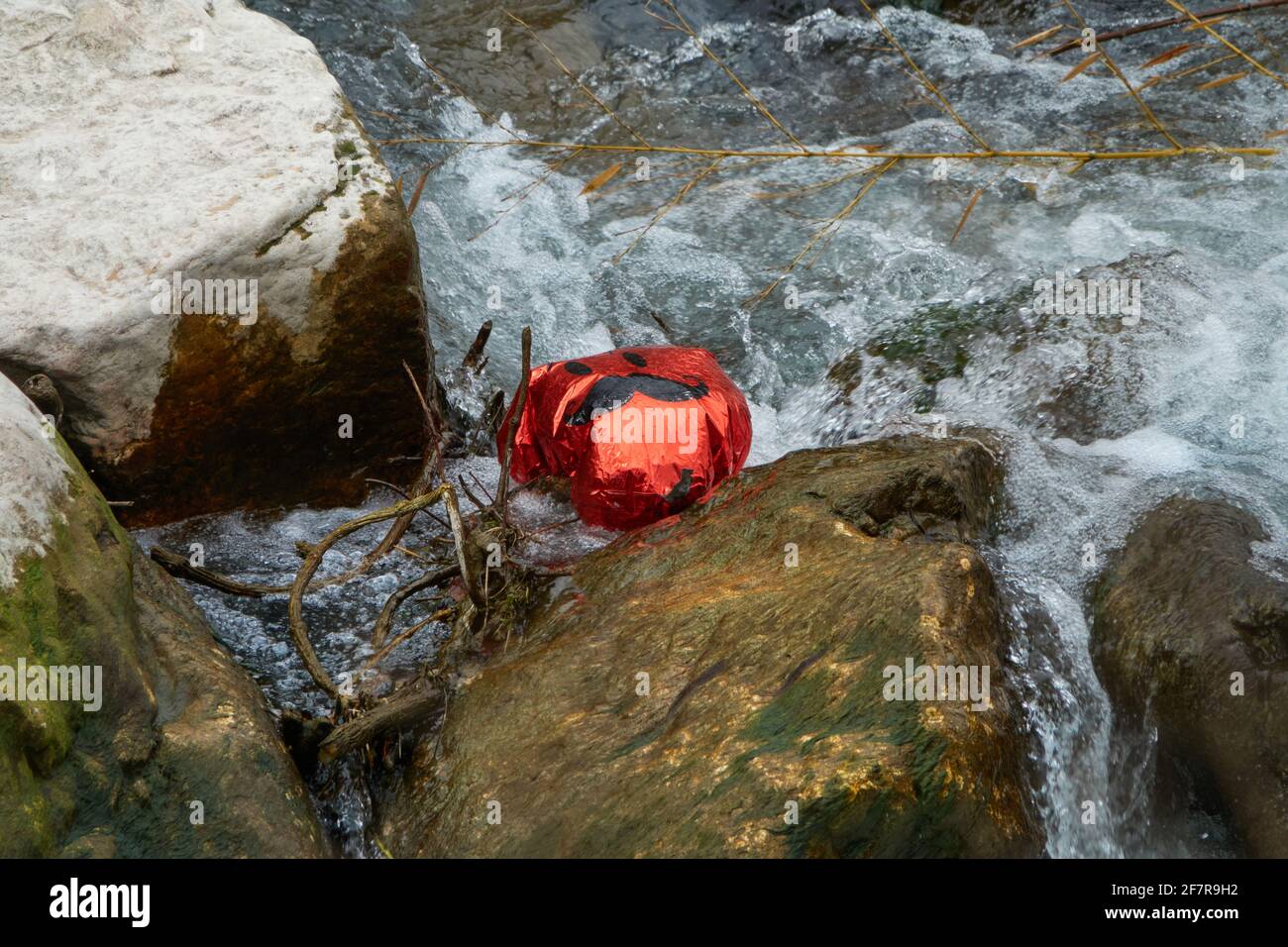 Sulla superficie dell'acqua galleggia un palloncino rosso con una faccia disegnata con baffi Foto Stock