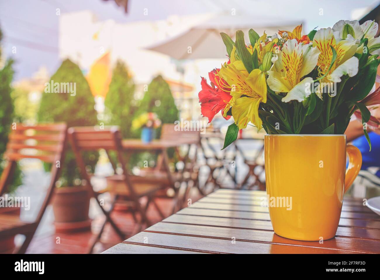 Romantica caffetteria, strada accogliente con fiori e tavolino da caffè in stile francese. Terrazza vuota con tavolo e sedia bianchi. Esterno rosa del cafe r Foto Stock