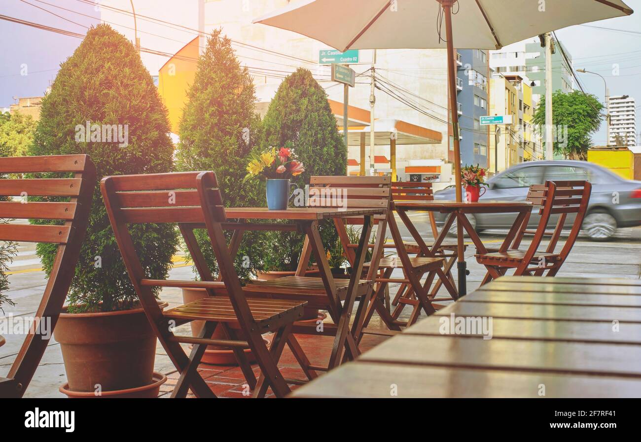 Romantica caffetteria, strada accogliente con fiori e tavolino da caffè in stile francese. Terrazza vuota con tavolo e sedia bianchi. Esterno rosa del cafe r Foto Stock