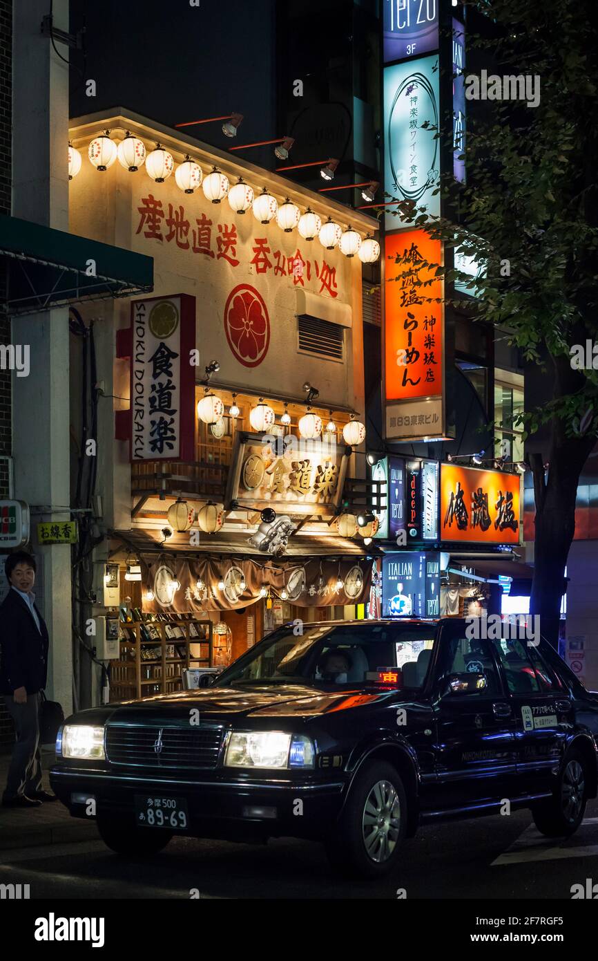 Vista notturna verticale di un taxi illuminato dalle lanterne torpenti e dai colorati cartelli al neon dei ristoranti Kagurazaka, Tokyo, Giappone Foto Stock