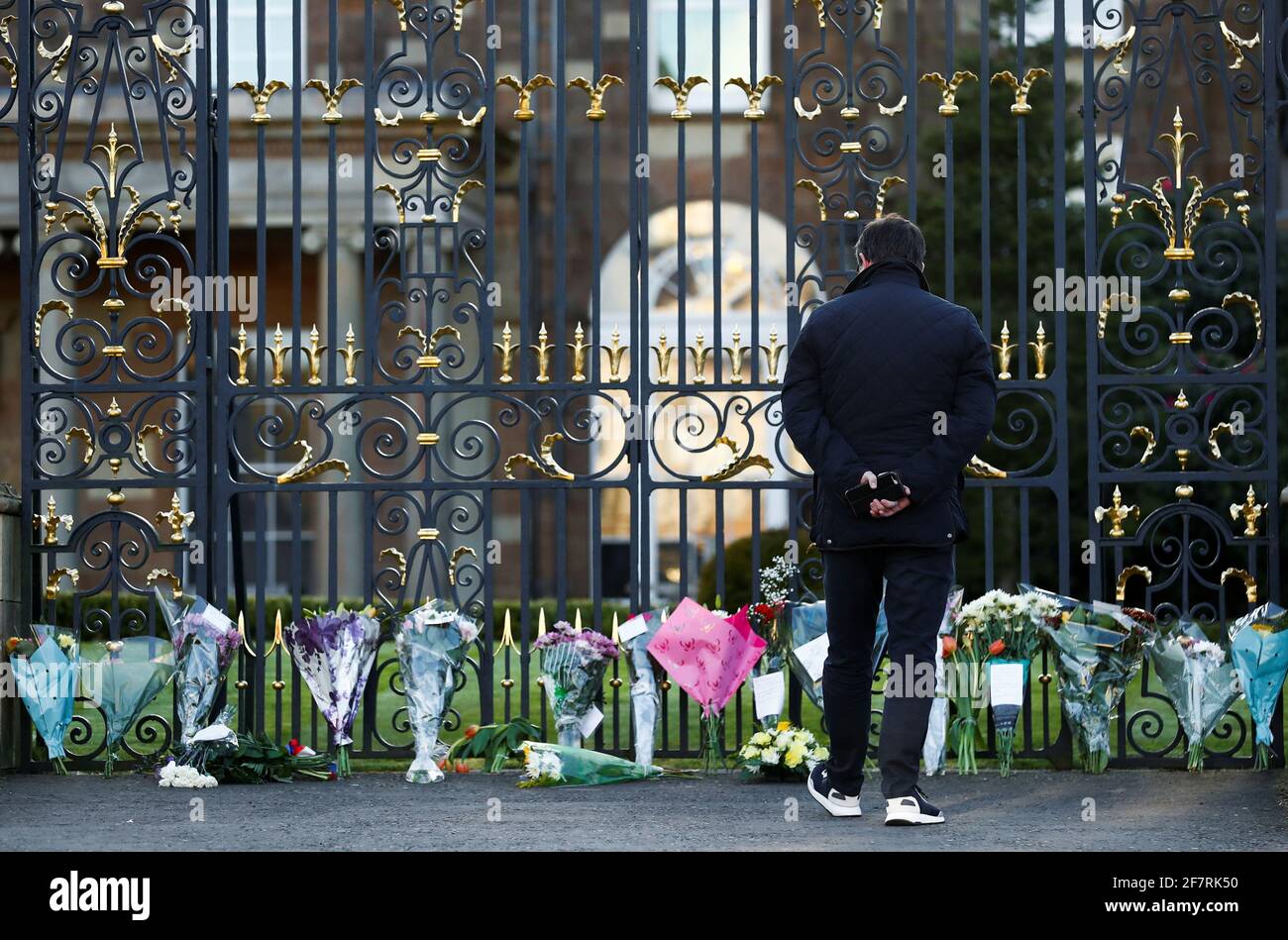 Un uomo si trova fuori dal castello di Hillsborough, mentre la gente porta i fiori, dopo che il principe Filippo della Gran Bretagna, marito della regina Elisabetta, morì all'età di 99 anni, a Hillsborough, Irlanda del Nord, il 9 aprile 2021. REUTERS/Jason Cairnduff Foto Stock