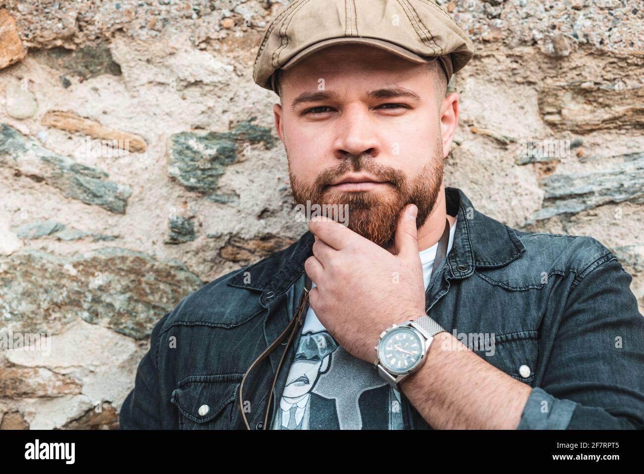 Ragazzo giovane, hipster che tiene la mano sotto il mento, pensando Foto Stock