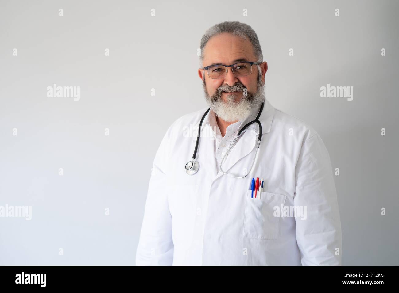 Ritratto di dottore anziano in camice bianco e fonendoscopio su sfondo bianco. Foto Stock