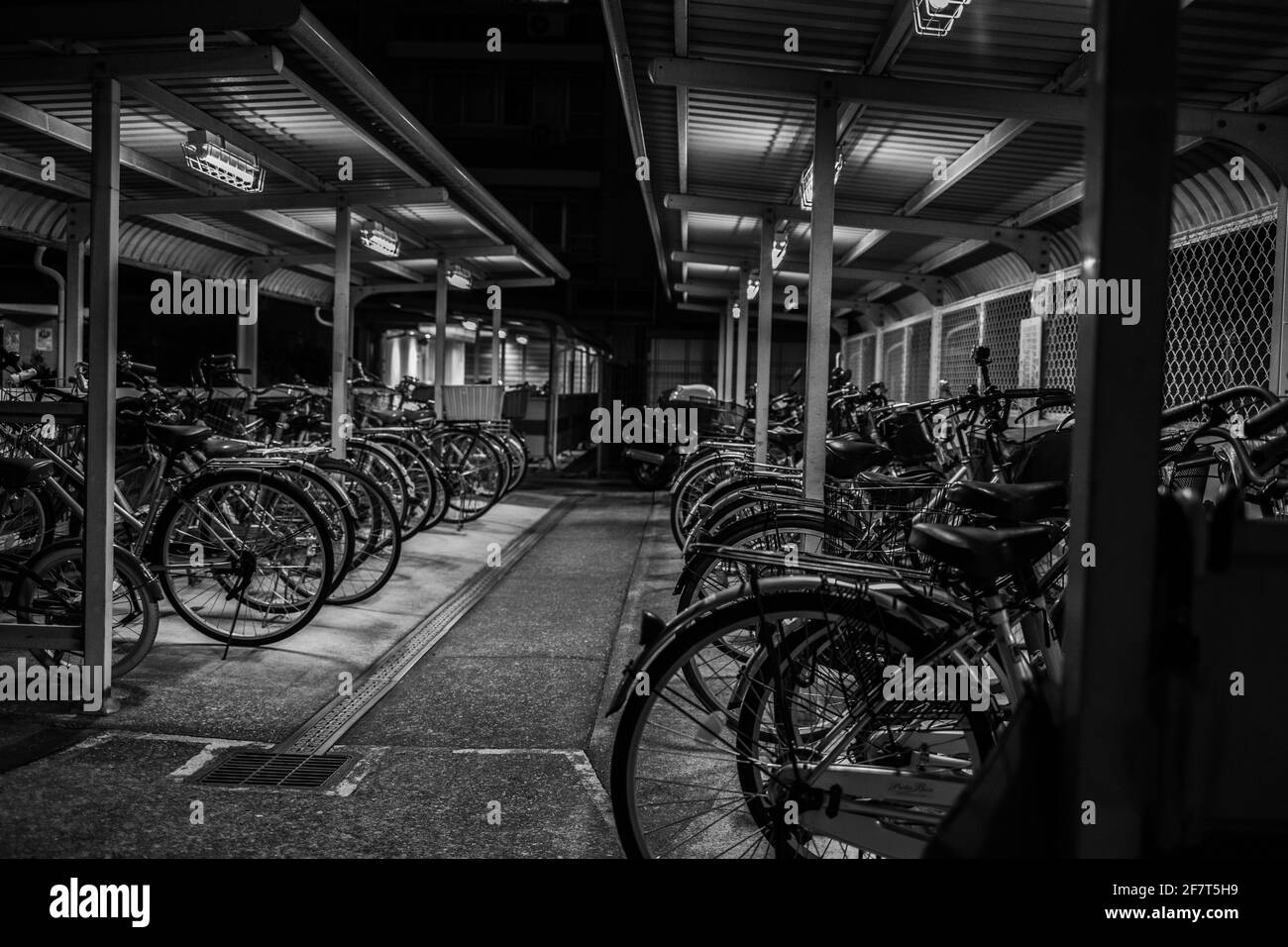 Tiro in scala di grigi di biciclette in una zona di parcheggio sotterraneo Foto Stock