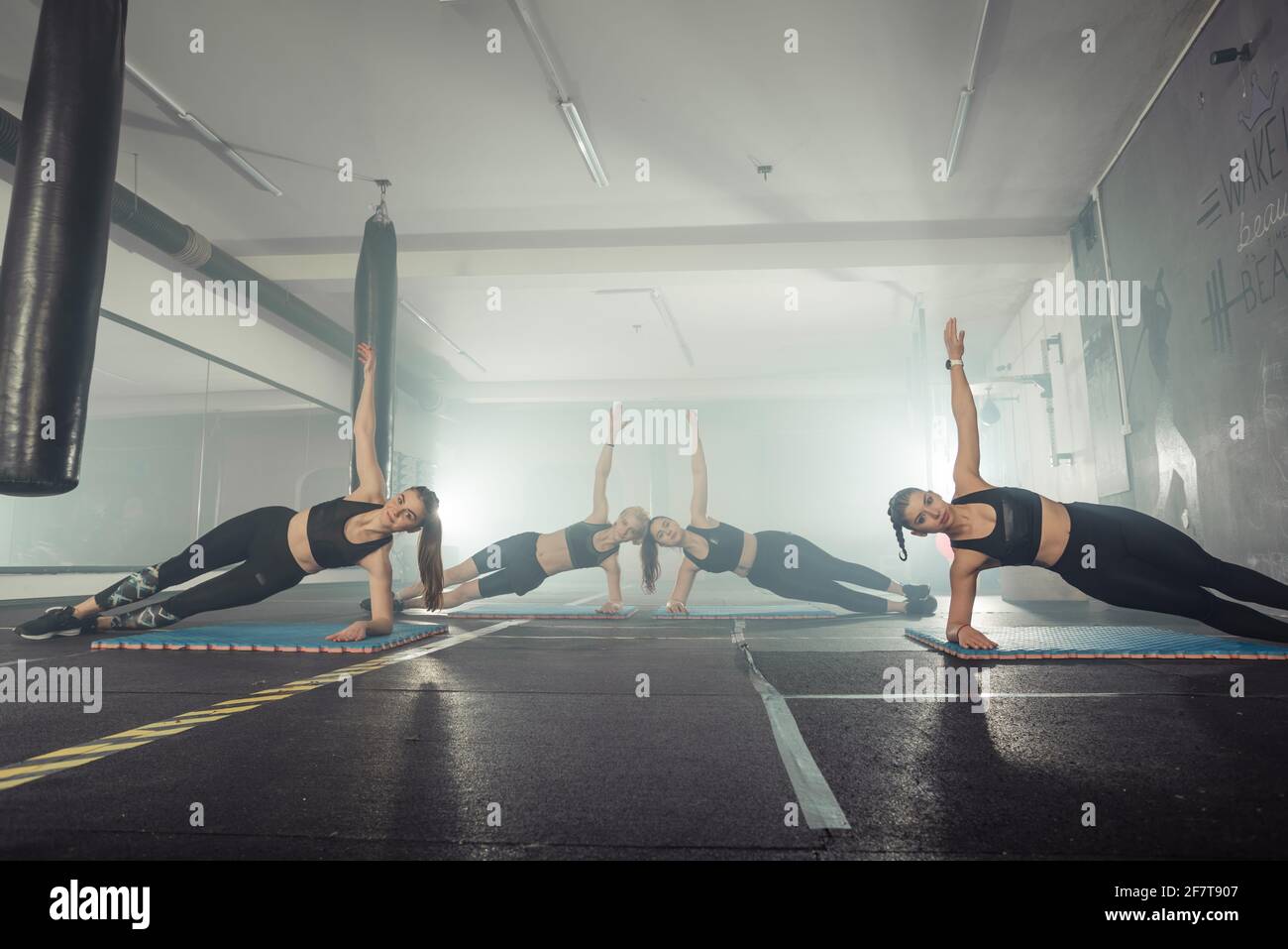 Donne in bianco e nero abbigliamento sportivo su un vero gruppo corpo combattimento allenamento in palestra treno per combattere, kickboxing con un allenatore. Foto Stock