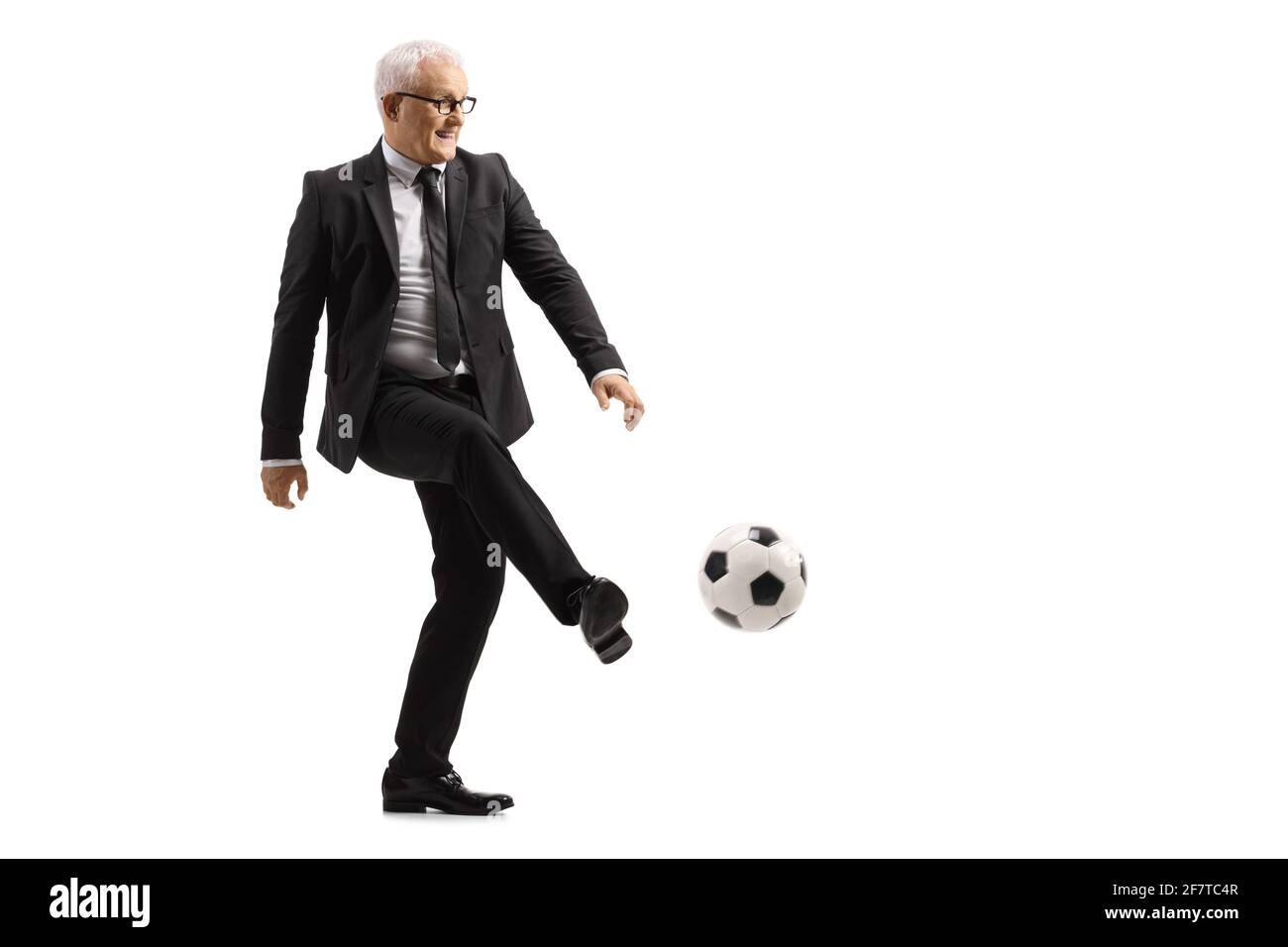 Foto di profilo a lunghezza intera di un uomo d'affari maturo che calcia un calcio isolato su sfondo bianco Foto Stock