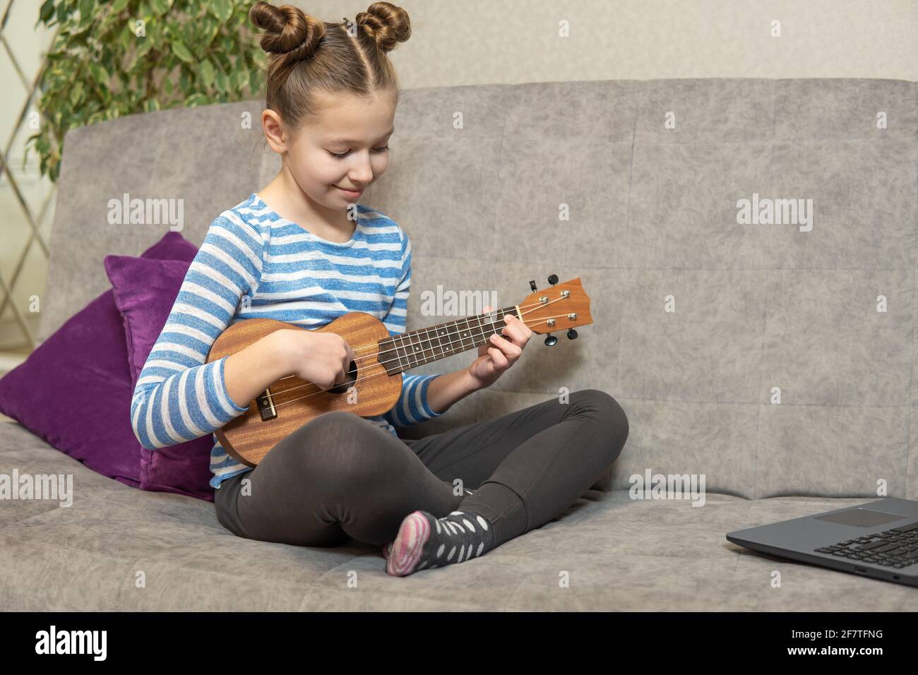 I bambini imparano lezioni di musica online a casa. Homeschooling e formazione a distanza per i bambini. Studentessa studia online con videochiamata insegnante giocare a. Foto Stock