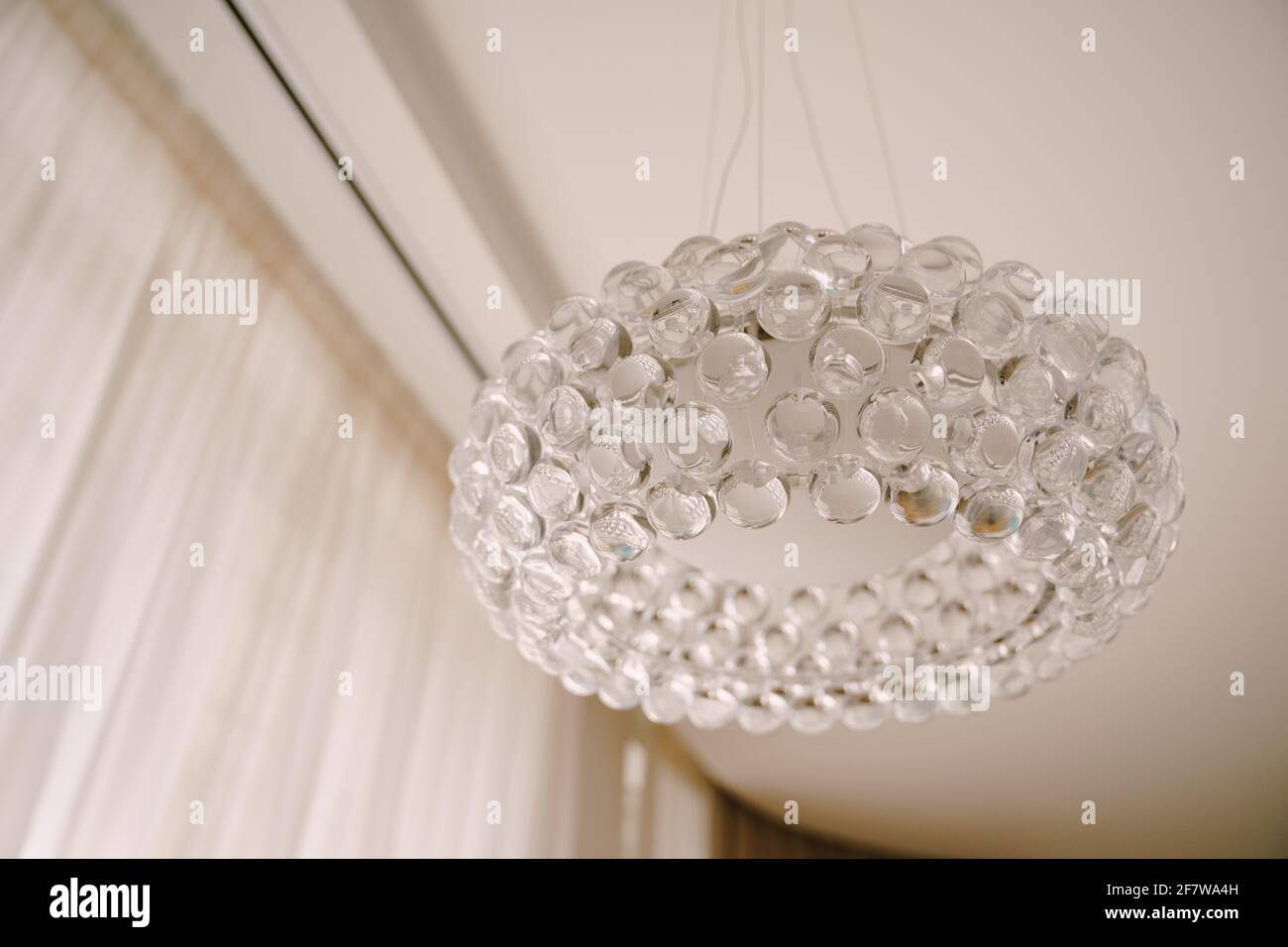 Elegante lampadario hi-tech realizzato con palline acriliche trasparenti. Interni con luce bianca. Foto Stock