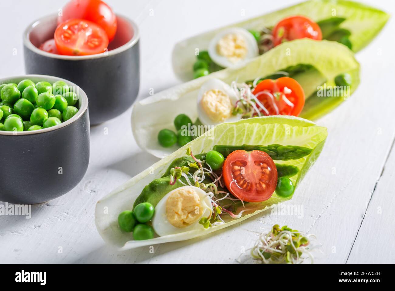 Decomposizione dell'insalata in cicoria fatta di pomodori, uova e piselli. Decomposizione personalizzata dell'insalata. Foto Stock