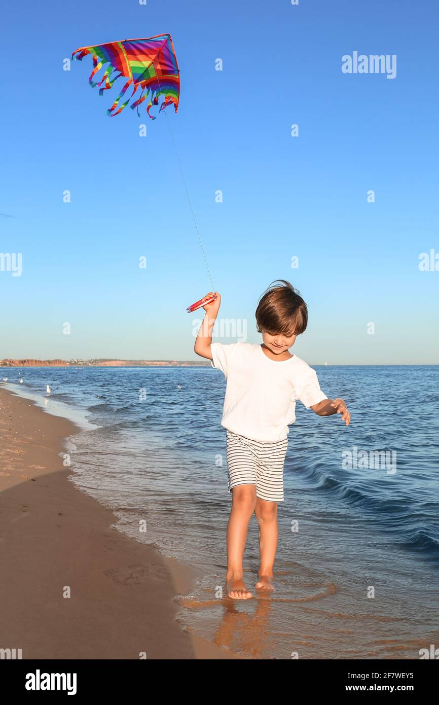 Carino ragazzino che vola aquilone arcobaleno sulla spiaggia di mare Foto  stock - Alamy