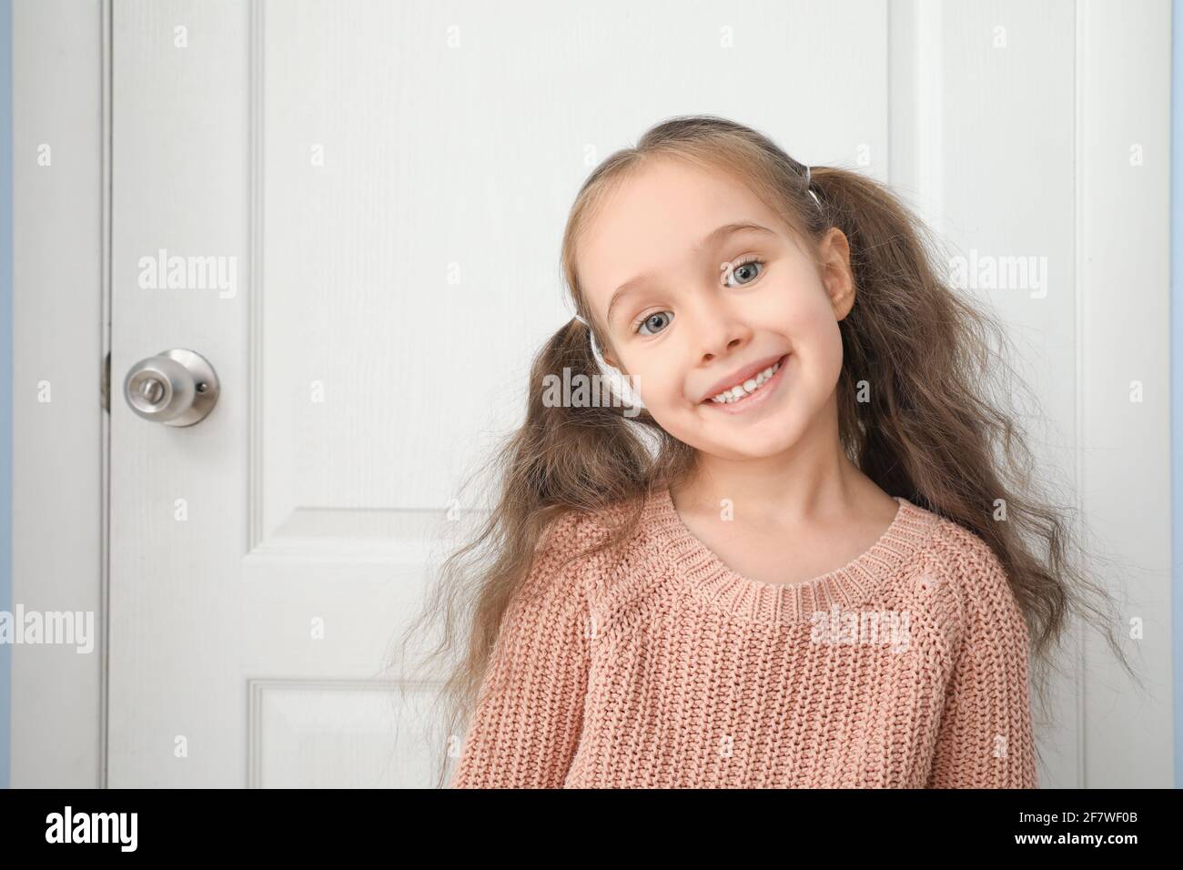 Carina bambina in piedi vicino alla porta chiusa Foto Stock