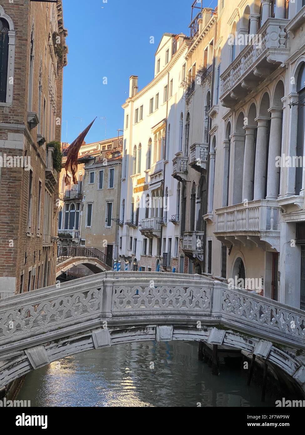 Bel ponte su un piccolo canale fiancheggiato, su sfondo colorato edificio, Venezia, Italia, durante la crisi di Lockdown COVID-19 Foto Stock