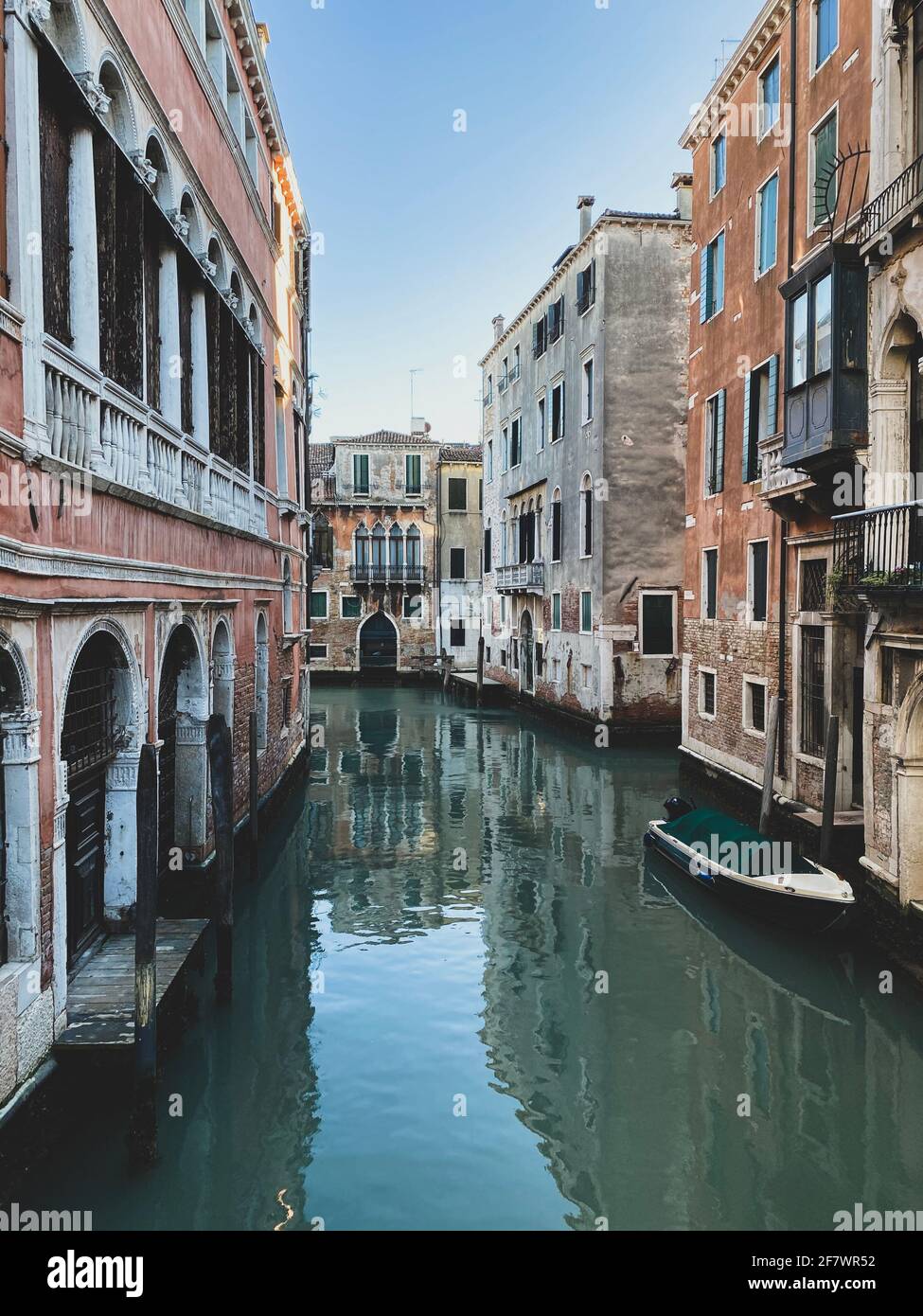 Piccola barca su una strada canale a Venezia con belle case colorate, Italia. Cielo blu Foto Stock