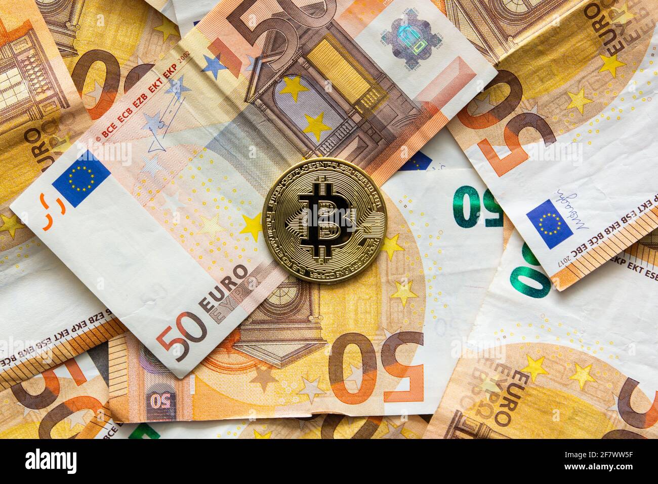 Vista dall'alto di una moneta di bit su uno sfondo di 50 euro di bollette. Bitcoin come nuovo denaro, mercato azionario di criptovalute e concetto di finanze decentralizzate Foto Stock