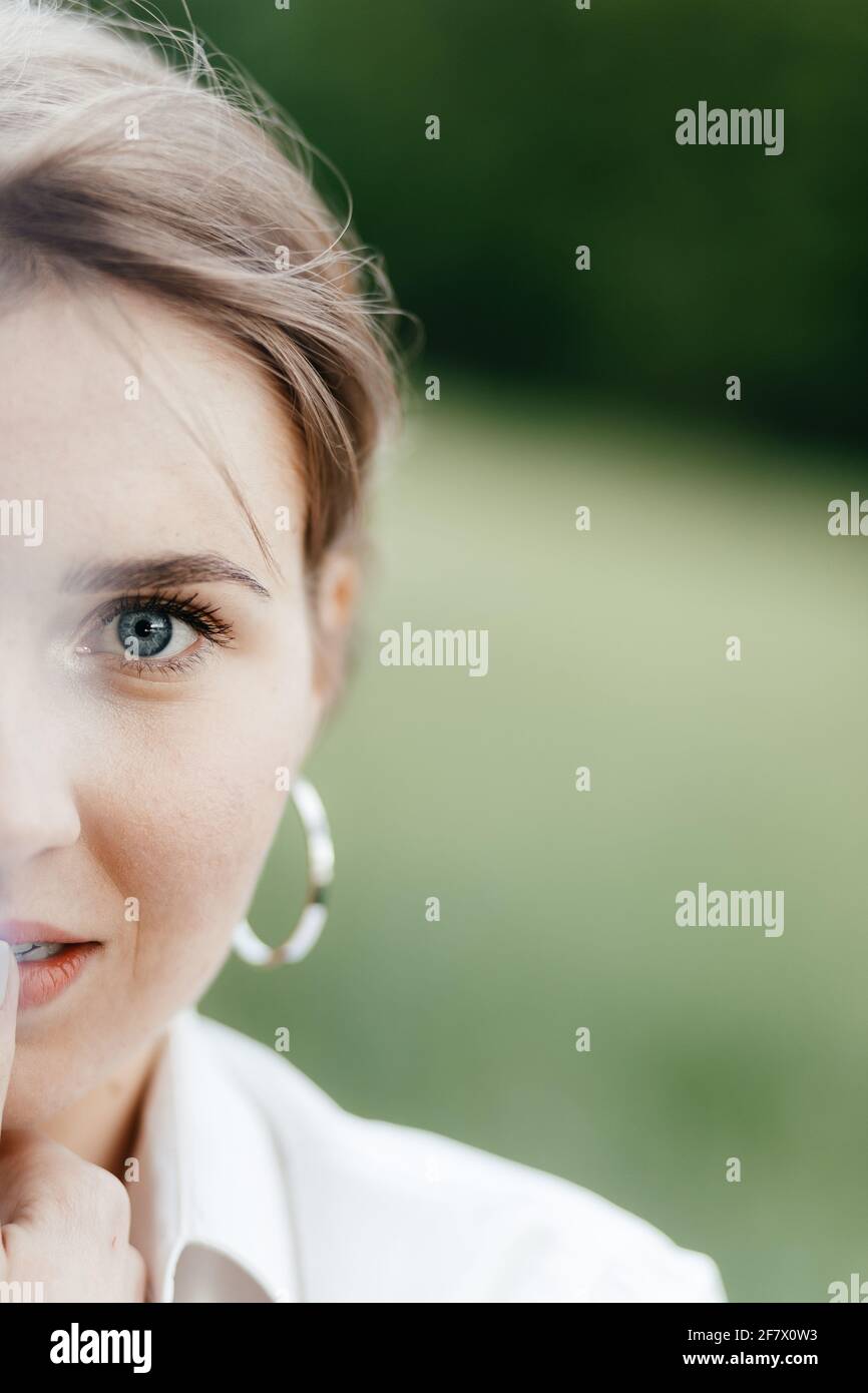 Metà faccia in primo piano di giovane bella ragazza sorridente con grandi orecchini rotondi. Inserire il testo. Foto Stock