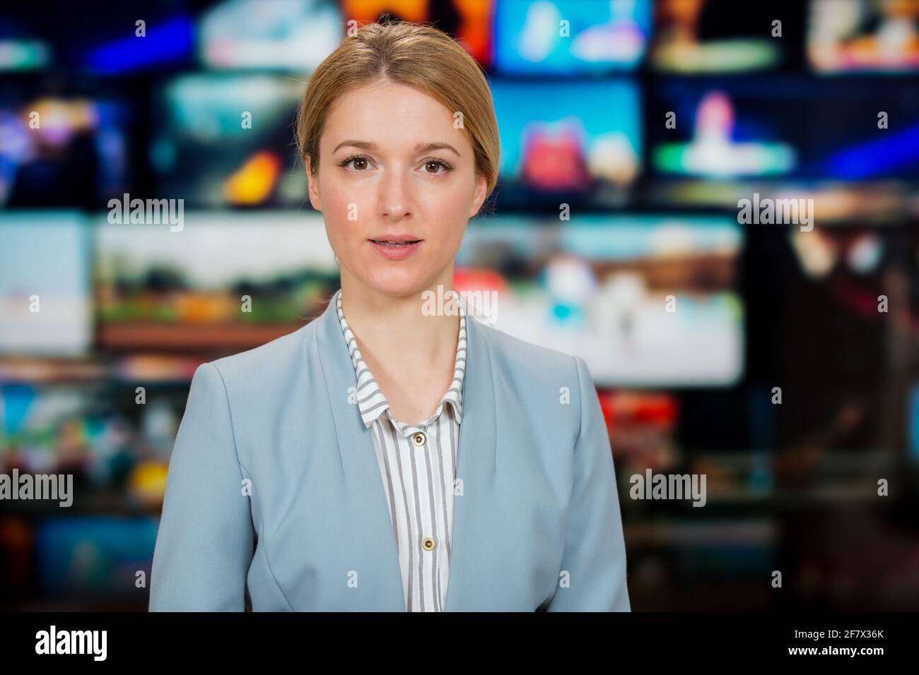 Una anchorwoman che riporta notizie dal vivo in studio TV. Sfondo di più schermi della sala di controllo delle trasmissioni. Concetto di giornalismo Foto Stock