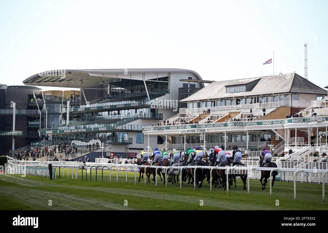 I corridori e il pilota passano la tribuna, con la bandiera di Union Jack a metà albero, al primo giro nell'ostacolo dell'EFT Systems Handicap durante la Grand National Day del Randox Health Grand National Festival 2021 all'ippodromo di Aintree, Liverpool. Data immagine: Sabato 10 aprile 2021. Foto Stock