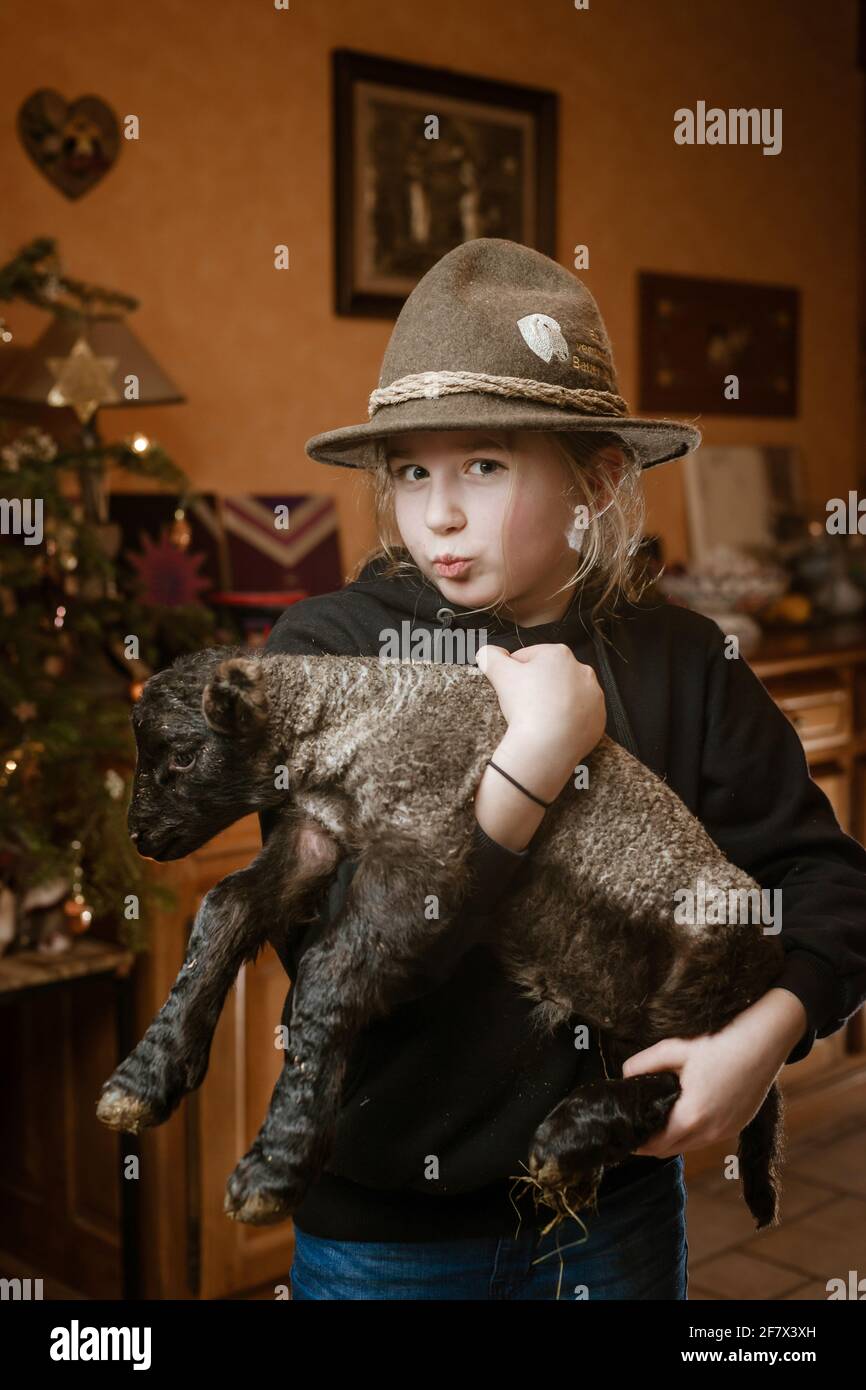 Una ragazza nel cappello di un pastore con un giovane agnello neonato tra  le braccia Foto stock - Alamy