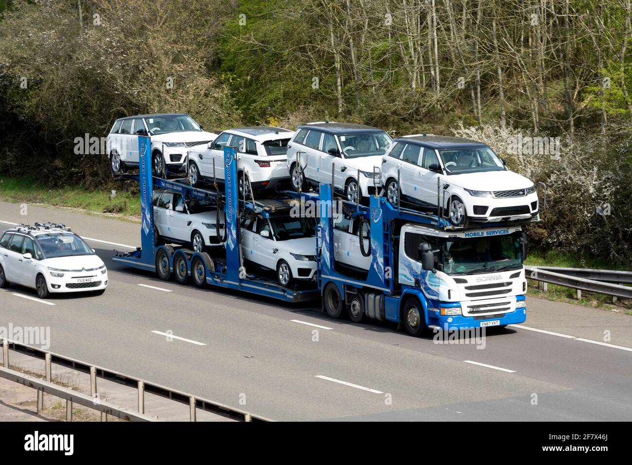 Un autocarro Scania Mobile Services che trasporta nuove auto bianche Land Rover sull'autostrada M40, Warwickshire, Regno Unito Foto Stock