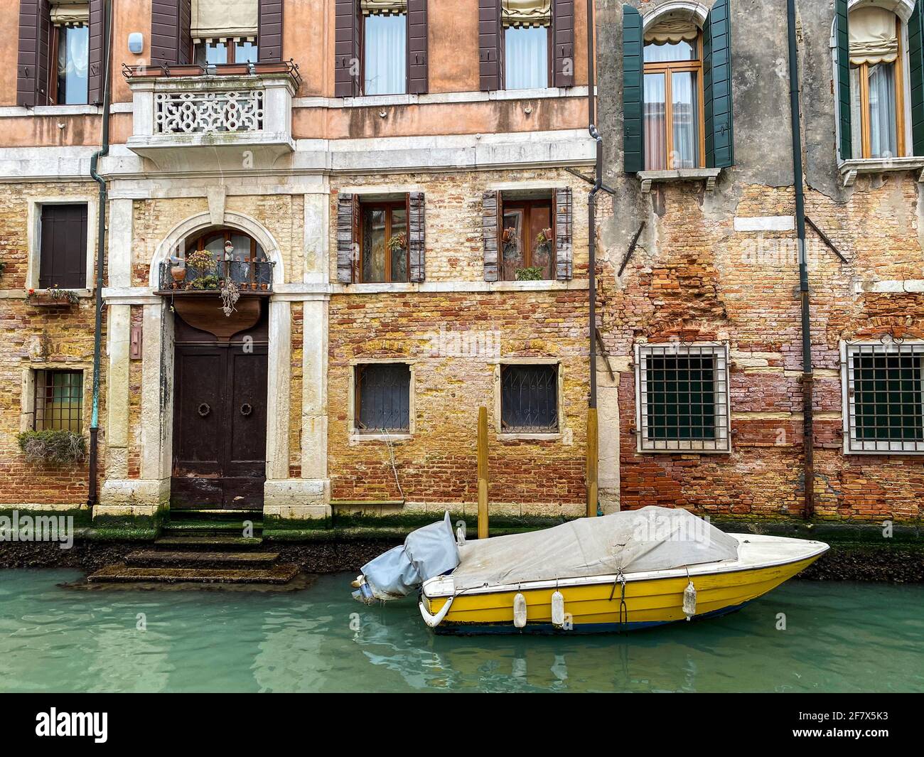 Vista laterale di un attracco giallo di fronte una casa veniziana Foto Stock