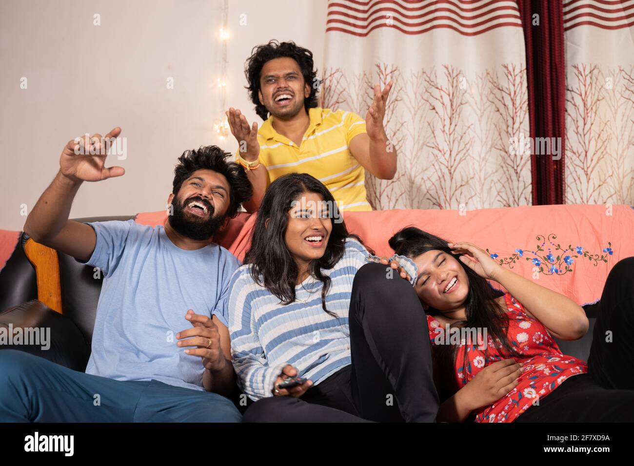 Gruppo di amici millennial ridendo fuori forte sopra guardare la commedia o la scena divertente mentre vedono la serie in linea di film di fotoricettore sulla televisione Foto Stock