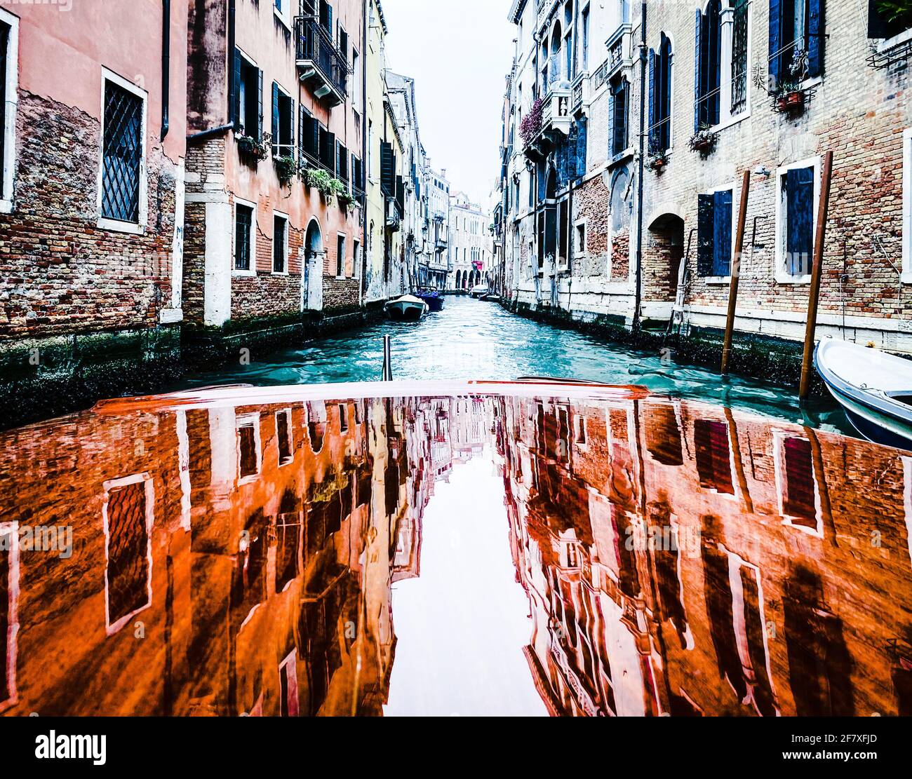 Riflessione delle case sulla cappa in legno verniciato, pontile, del taxi acqueo nelle vie di Venezia, che parte Foto Stock