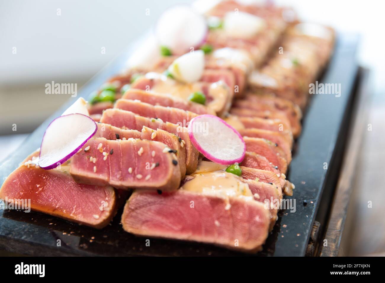 bistecca di tonno fresco tagliata a fette e servita su un piatto a. una festa Foto Stock