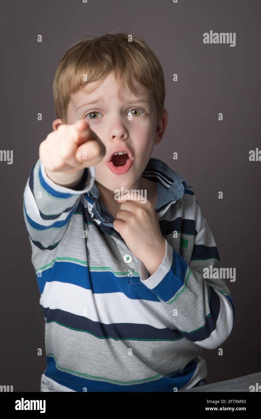 Young boy punta alla telecamera in una posa in studio. Foto Stock