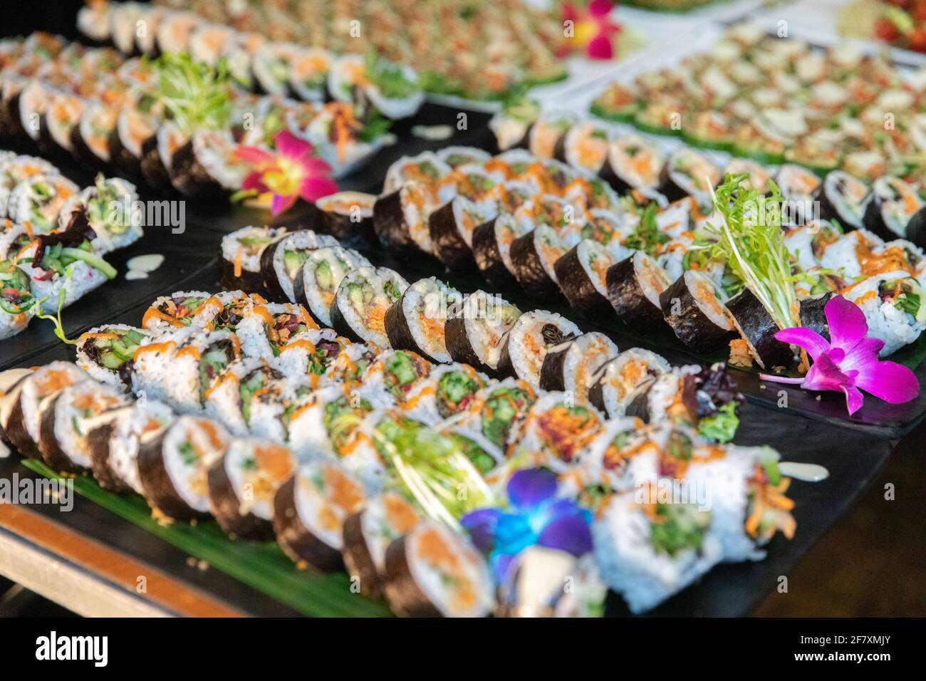 Presentazione di un sacco di sushi fresco affettato su un piatto ad un evento con fiori Foto Stock