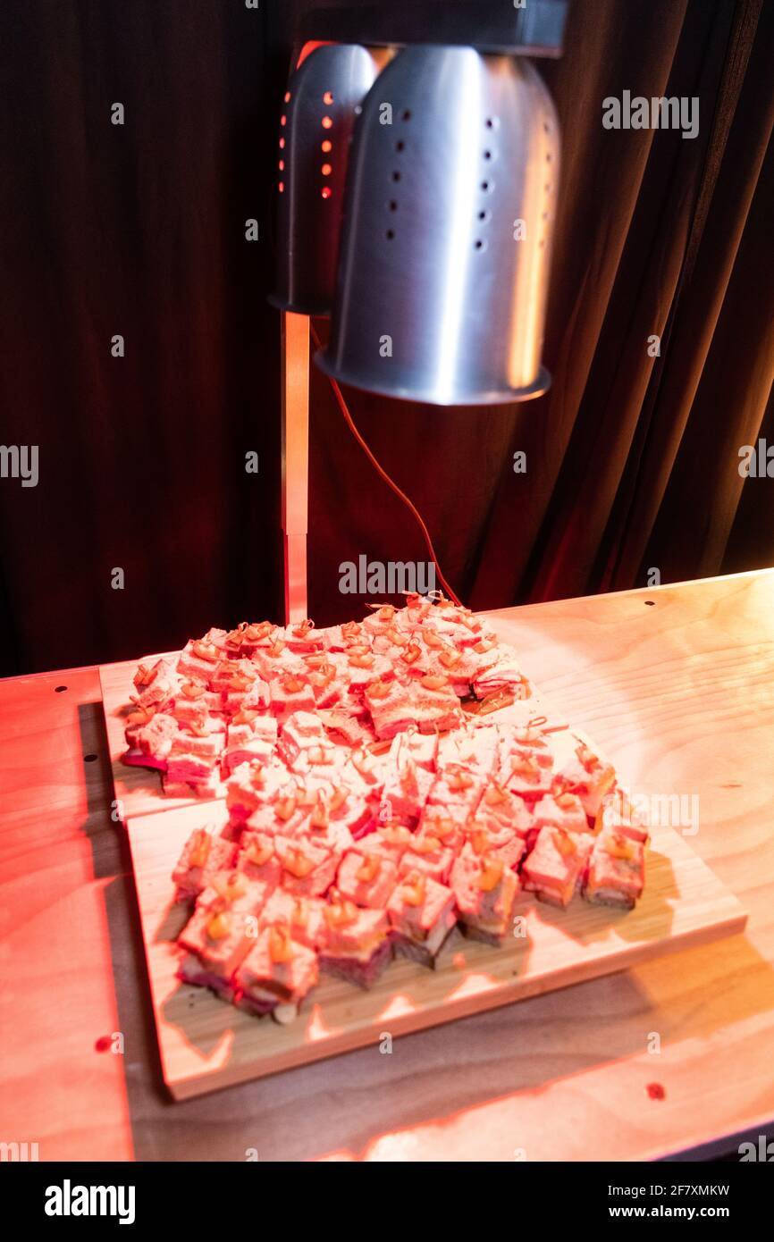 Lampada rossa che riscalda un piatto con antipasti su un tavolo pronto per essere servito Foto Stock