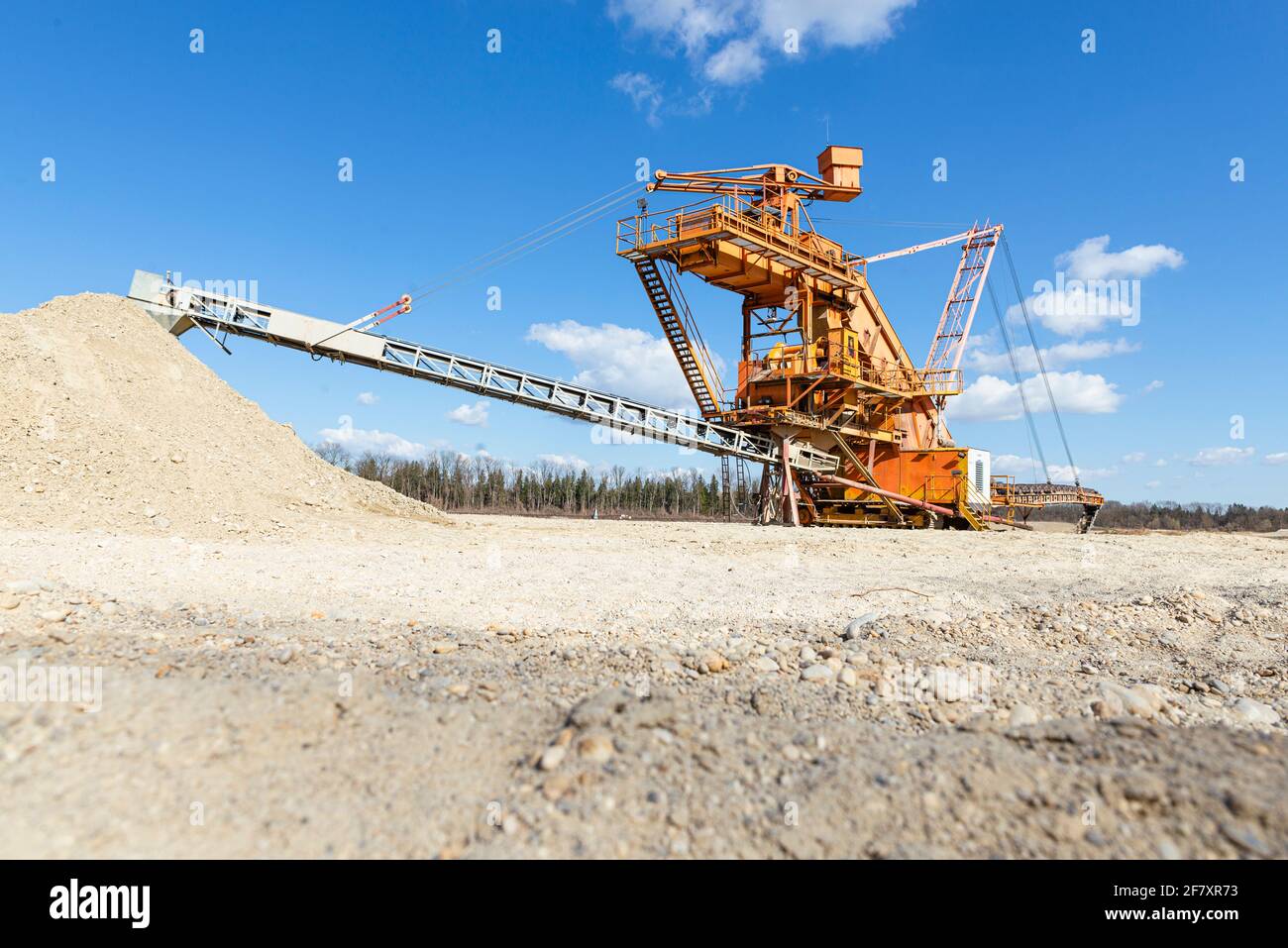 Draga mobile di ghiaia arancione in un laghetto di cava alla luce del sole, Baviera, Germania Foto Stock