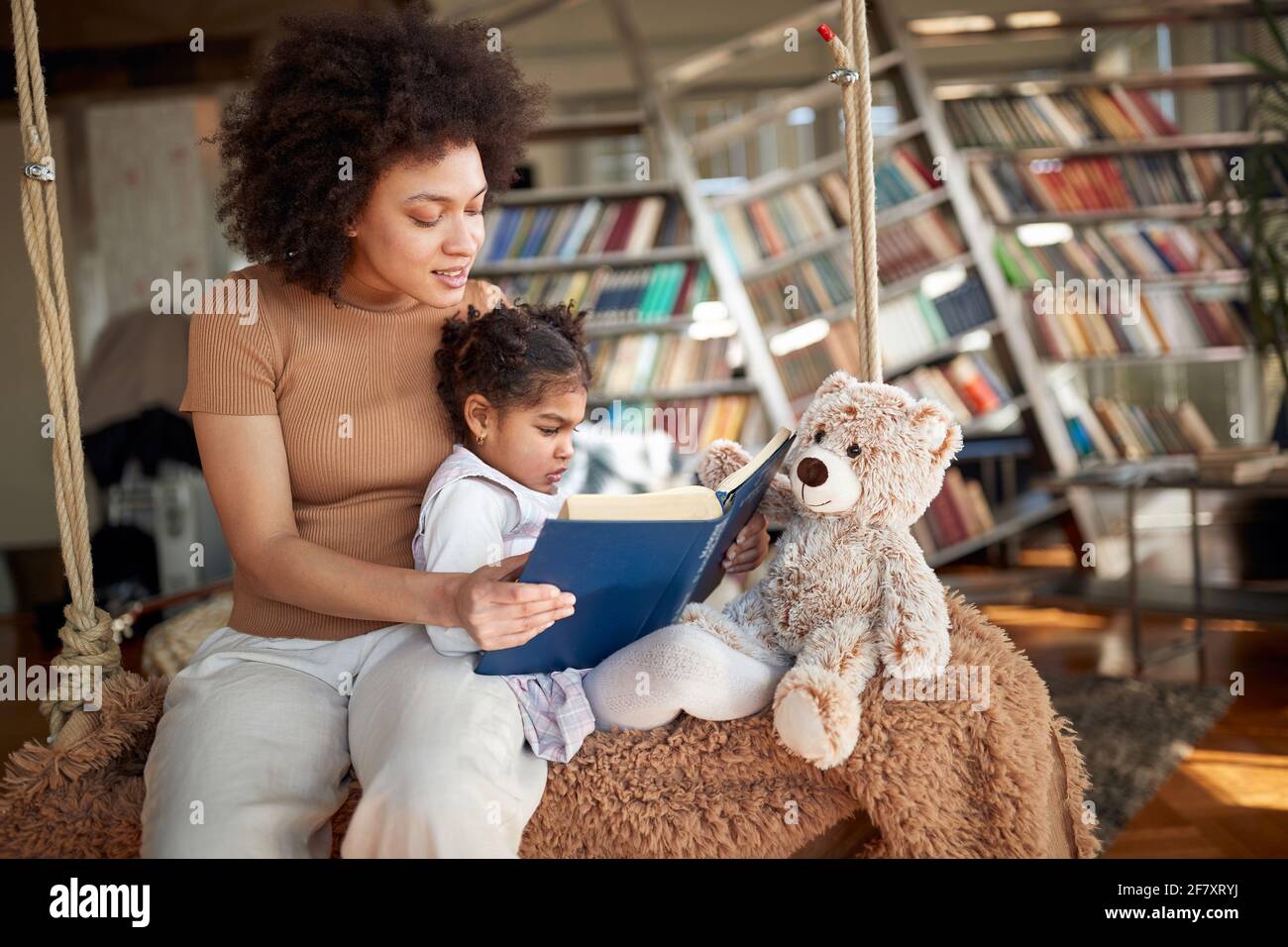 Madre afro-americana che legge la storia di addormentarsi alla figlia Foto Stock