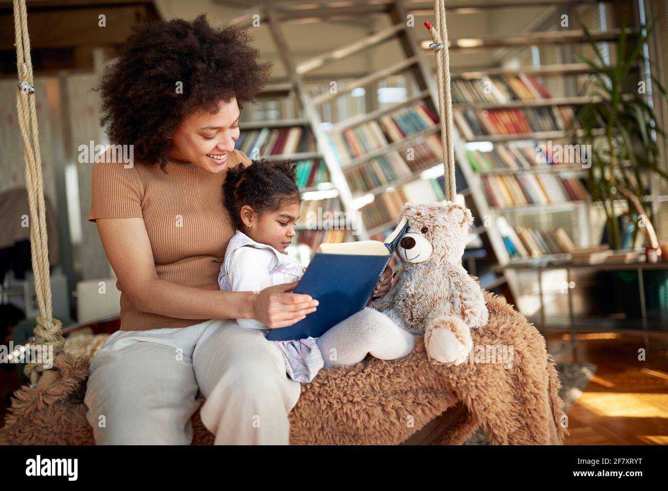 Felice afro madre americana che legge la storia di bedtime a sua figlia Foto Stock