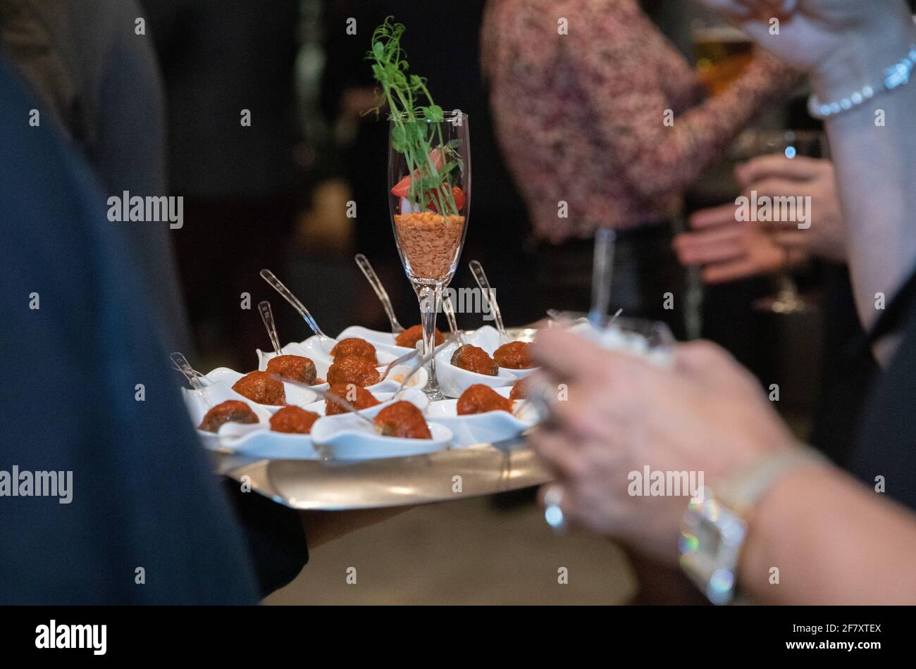 Cameriere che tiene un piatto riempito con piccoli stuzzichini tazze piccole con forchetta la sera Foto Stock