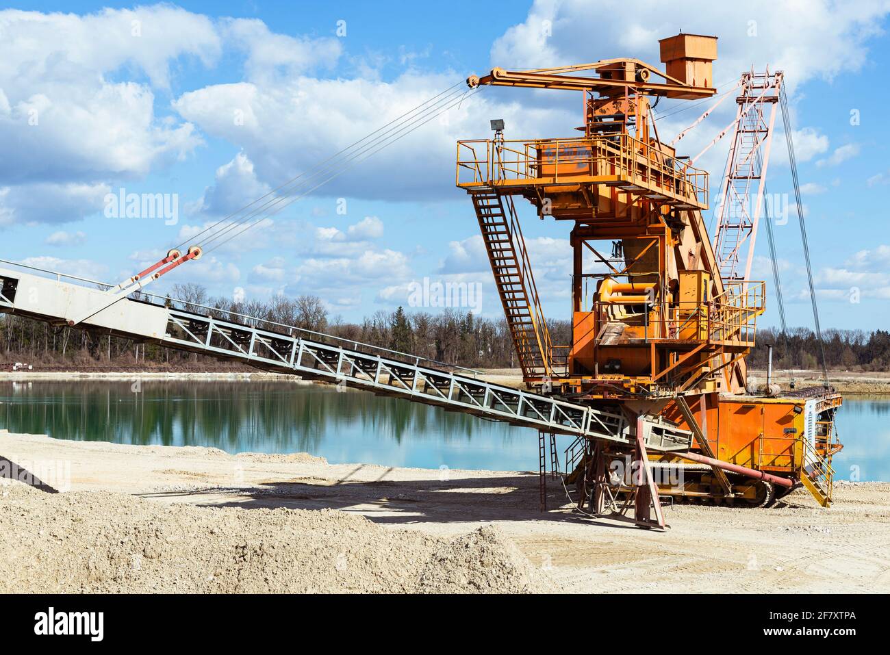 Draga mobile di ghiaia arancione in un laghetto di cava alla luce del sole, Baviera, Germania Foto Stock