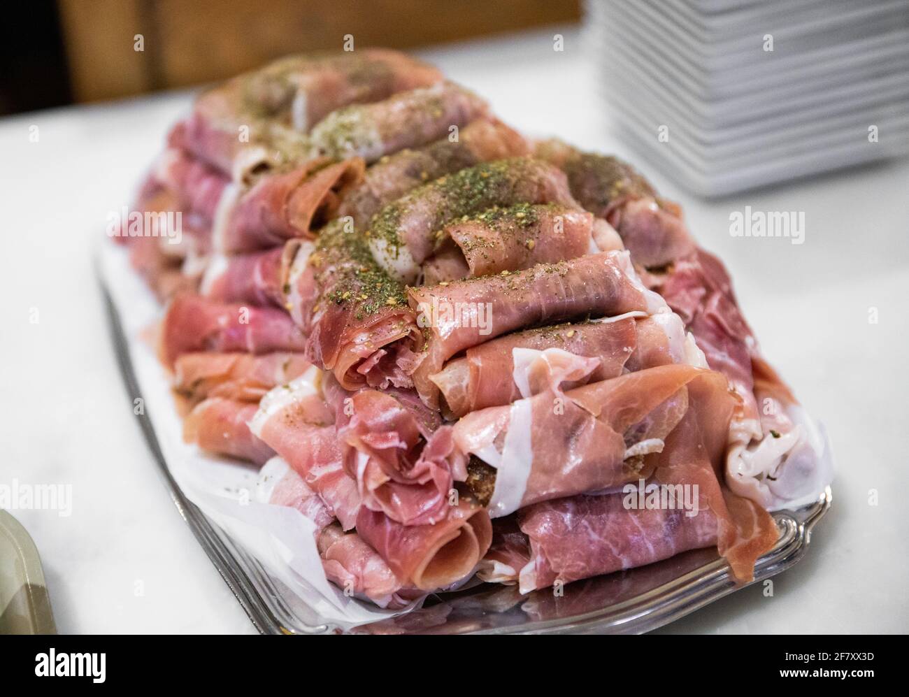piccole porzioni di cibo su un piatto con una forchetta e una mano che raggiunge per uno Foto Stock