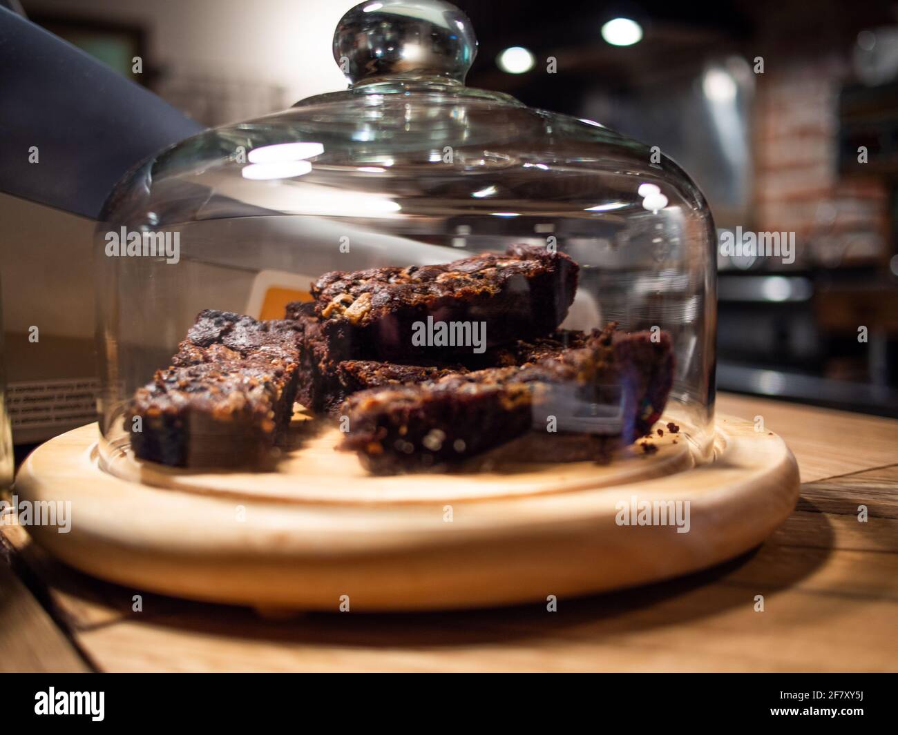 coperchio in vetro con un piatto di brownie al cioccolato al coperto sul banco di legno Foto Stock