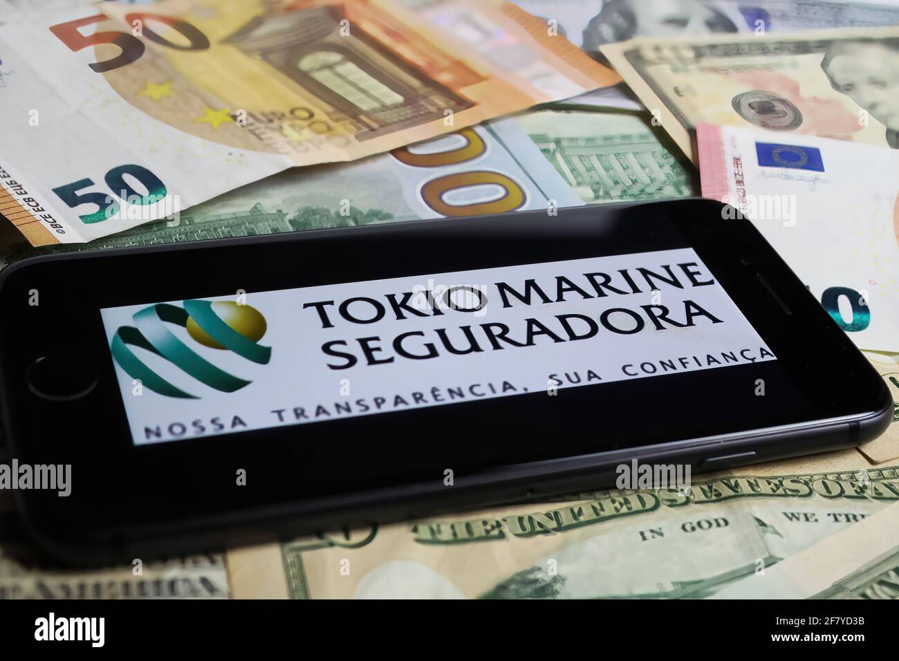 Viersen, Germania - 1 marzo. 2021: Closeup di smartphone con logo scritta di Tokio compagnia di assicurazione marina su carta moneta Foto Stock