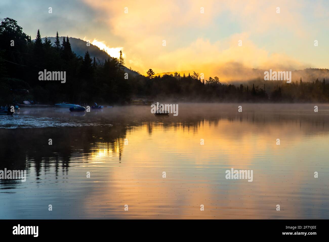 lago calmo su un'alba con un giocattolo gonfiabile dentro la distanza con cielo luminoso e giallo Foto Stock